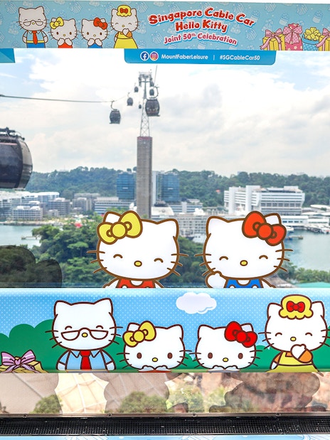 Singapore Cable Car decorated with Hello Kitty theme, overlooking cityscape and harbor.