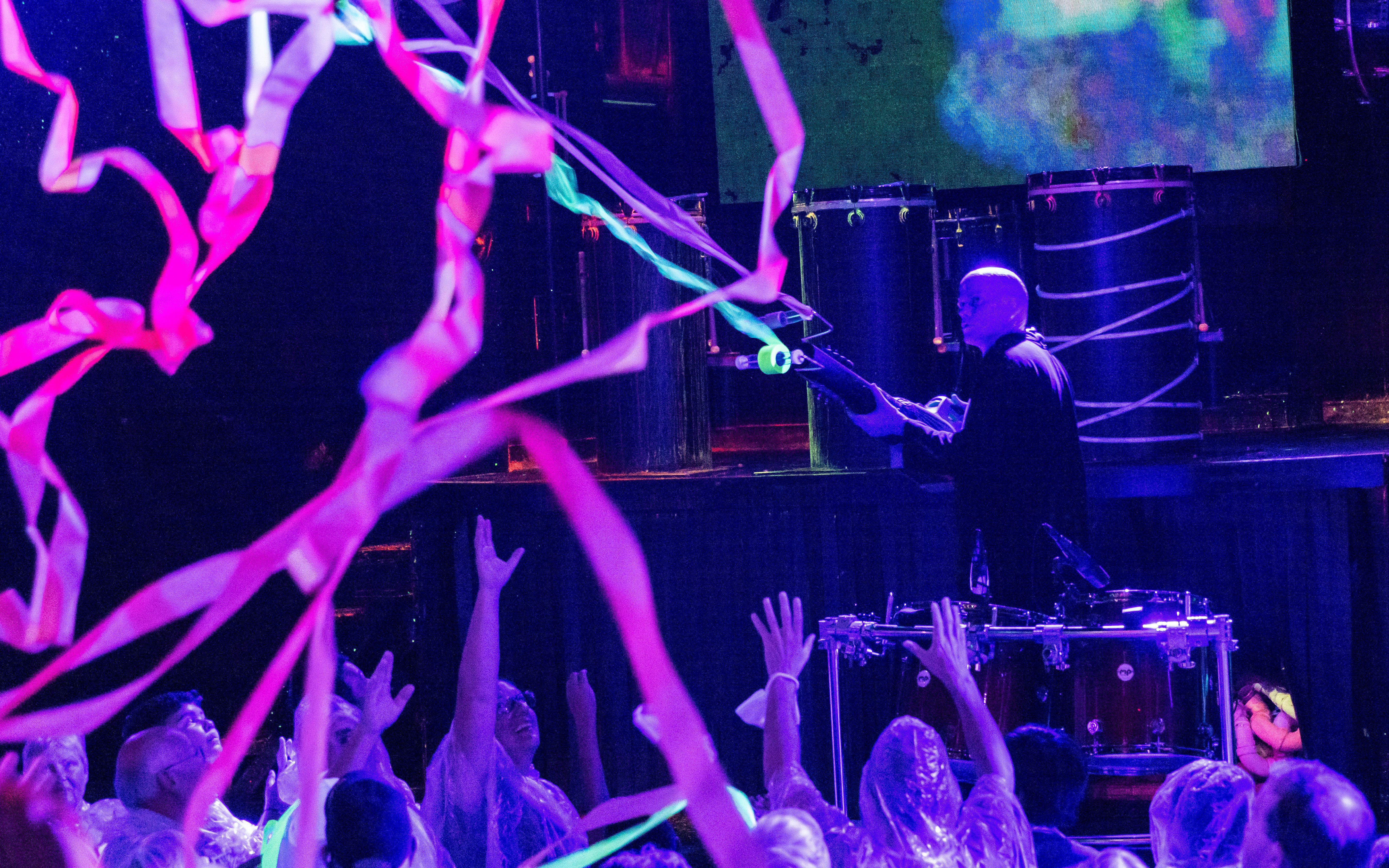 Blue Man Group performer on stage with audience in Orlando, colorful streamers in the air.
