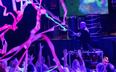 Blue Man Group performer on stage with audience in Orlando, colorful streamers in the air.