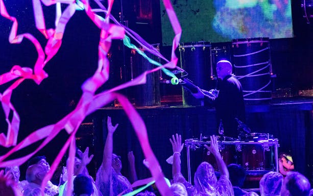 Blue Man Group performer on stage with audience in Orlando, colorful streamers in the air.