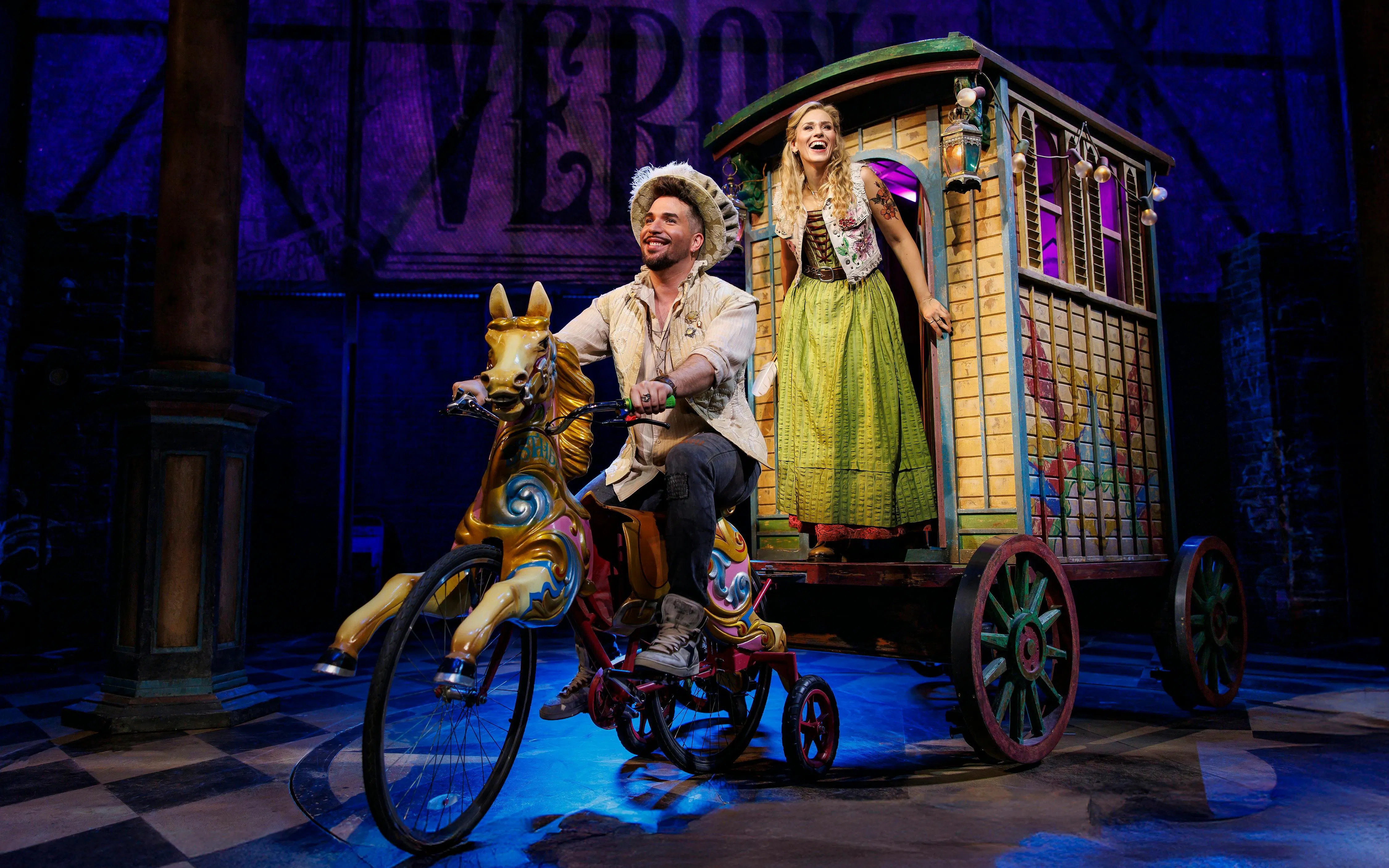 Stage scene from &Julia musical in Hamburg with performers on a whimsical bicycle and cart.