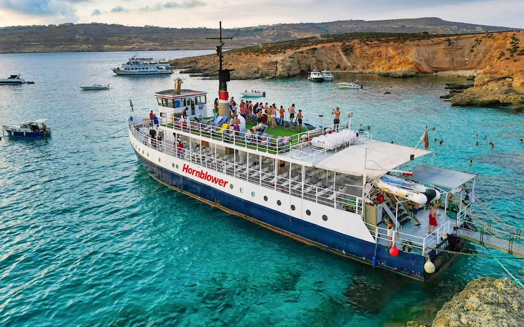 Cruise ship at Blue Lagoon with tourists enjoying the view and swimming in clear waters.