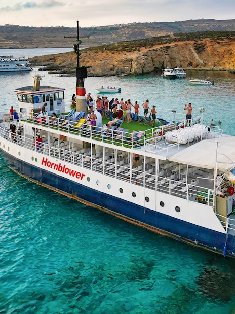 Cruise ship at Blue Lagoon with tourists enjoying the view and swimming in clear waters.