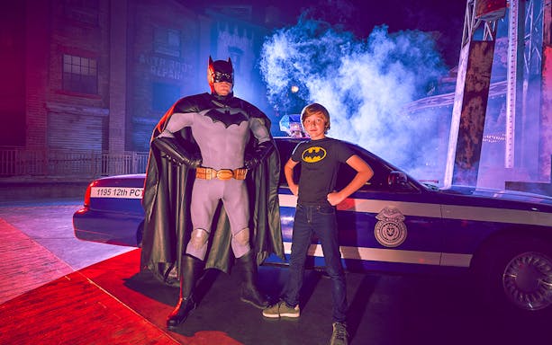 Superhero and child pose by police car at Yas Island park.