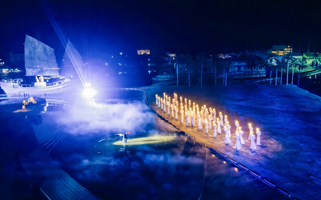 Performers with lanterns at Hoi An Memories Show, Vietnam, near illuminated ship.