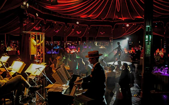 Burlesque performer on stage at The Mirage dinner show, Vienna, with live musicians.