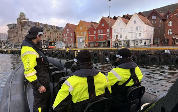 Tour group arriving by boat at a colorful waterfront city with historic wooden houses.