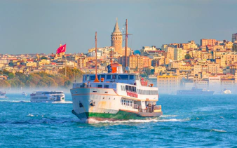 Old ferry steamboat on Bosphorus with Galata Tower and Karakoy district in Istanbul, Turkey.