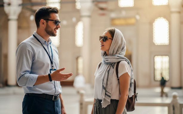 Tour guide speaking with woman tourist inside Suleymaniye Mosque, Istanbul.