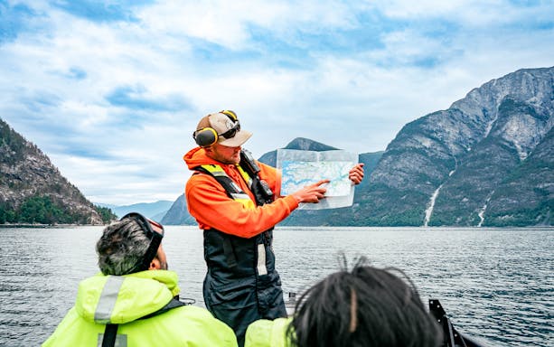 Guide explaining sea map to guests during Whale Watching tour in Husavik.