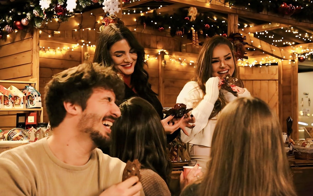 People enjoying festive treats at a Christmas market stall during a Budapest cruise.