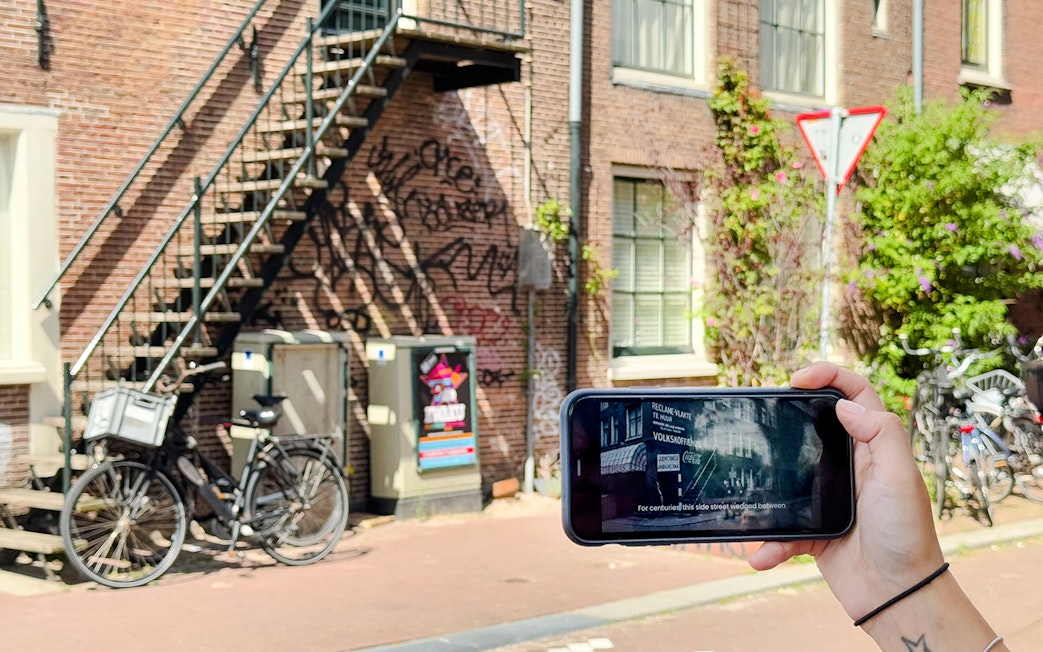 Mobile-guided tour in Amsterdam with a view of bicycles and historic buildings.