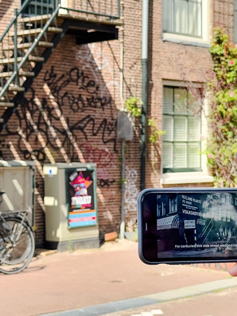 Mobile-guided tour in Amsterdam with a view of bicycles and historic buildings.