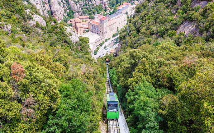 Cog-wheel train ascending to Montserrat Monastery with lush mountain views.