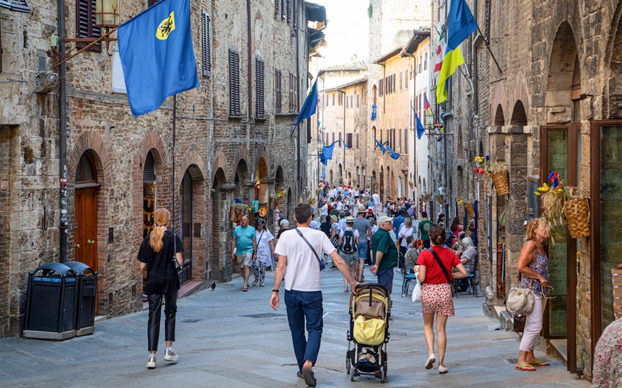 Crowded street in San Gimignano with tourists and medieval buildings.