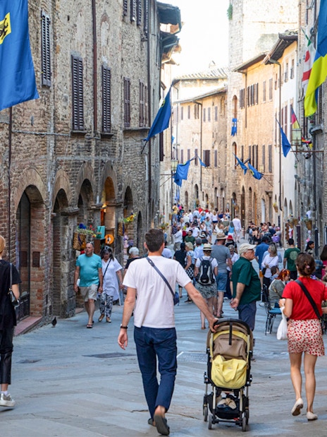 Crowded street in San Gimignano with tourists and medieval buildings.