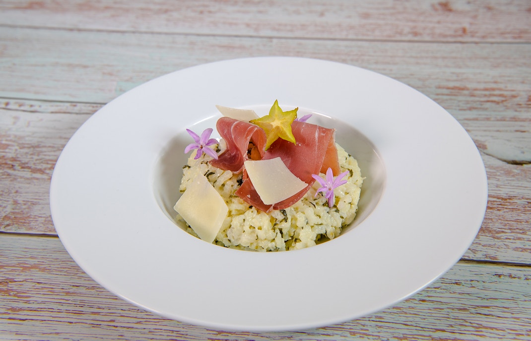Goat cheese risotto with prosciutto and starfruit garnish in Douro Valley.