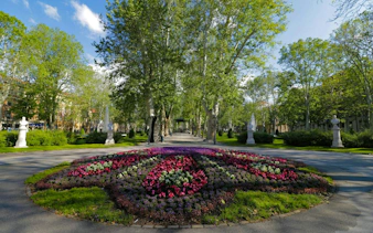 Zagreb park with colorful flower beds and tree-lined paths, part of self-guided city exploration game.