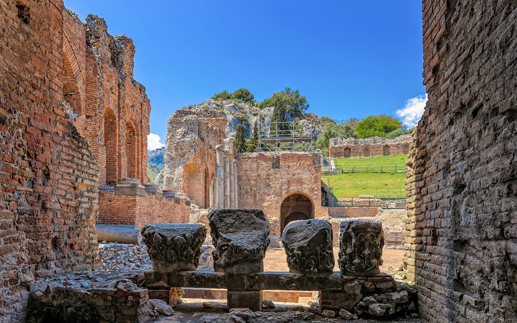 Ancient Theater of Taormina ruins with stone columns and archways, Sicily.