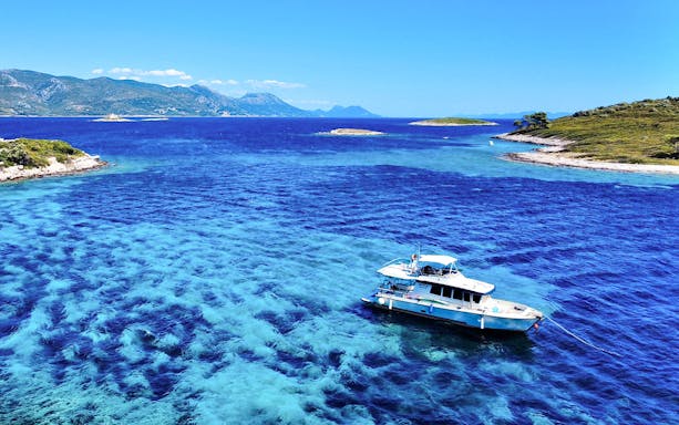 Boat anchored near hidden beaches in Korčula, Dubrovnik, ideal for snorkeling and swimming.