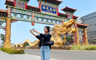 Person taking a selfie at the ornate entrance gate in Jakarta's Chinatown Glodok.