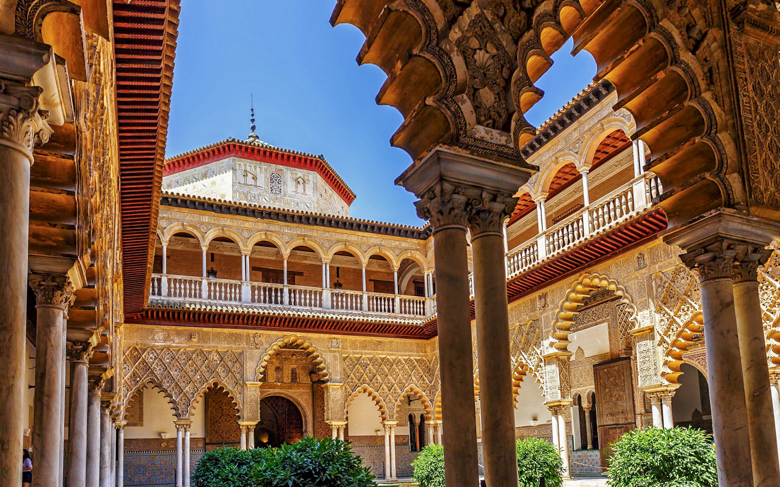Tour guide leading a group of tourists through the lush gardens of Alcazar of Seville during a Skip-the-Line Guided Tour