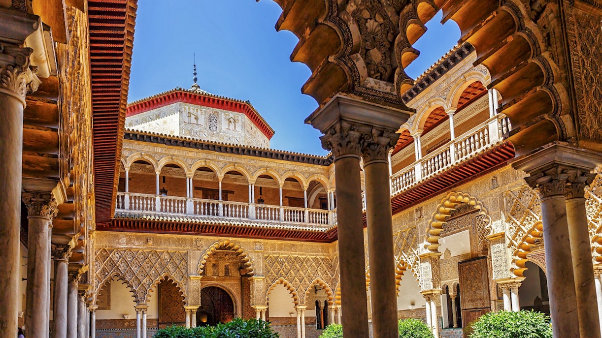 Tour guide leading a group of tourists through the lush gardens of Alcazar of Seville during a Skip-the-Line Guided Tour