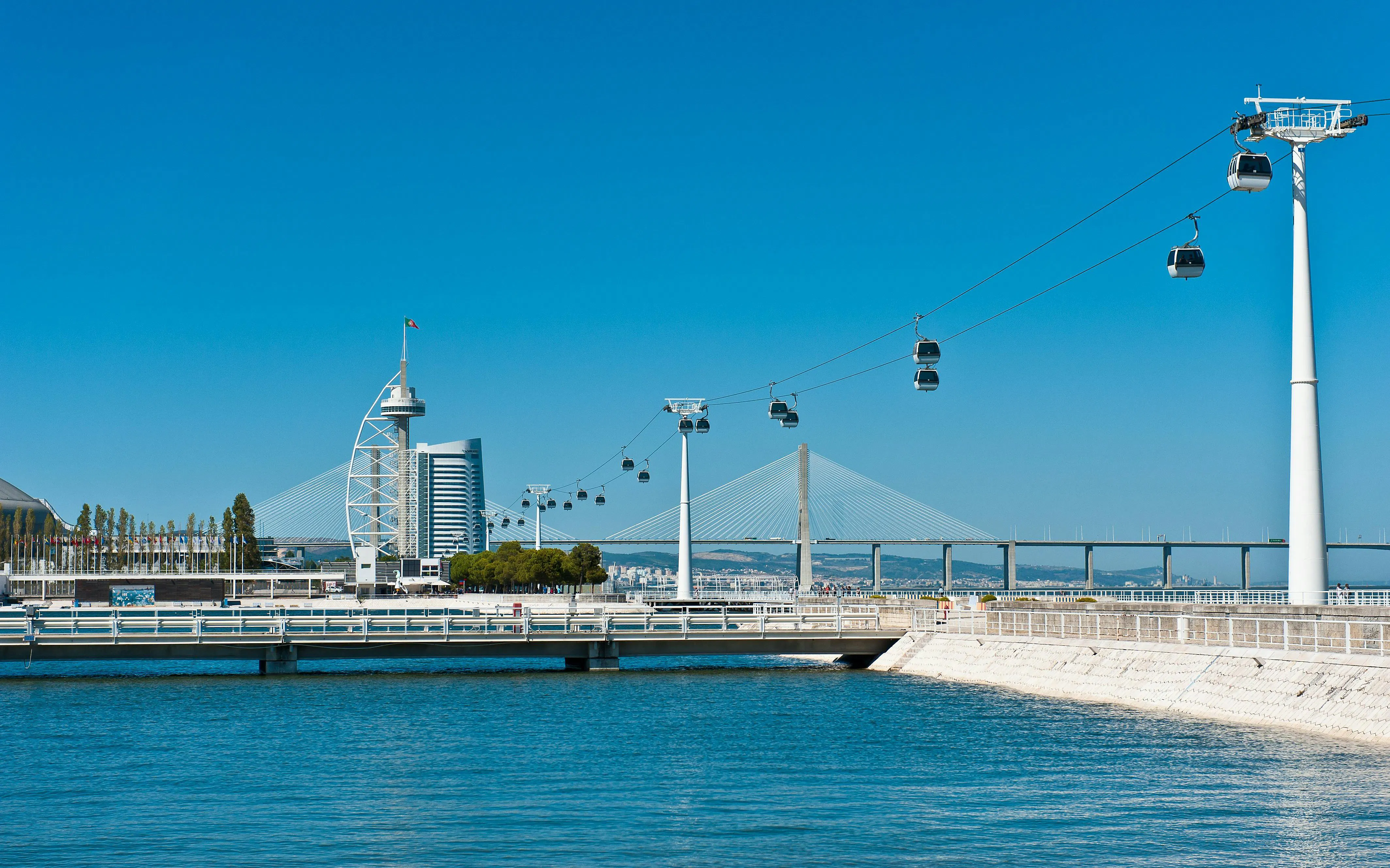 Cable cars over Tagus River with Vasco da Gama Tower and bridge in Lisbon.