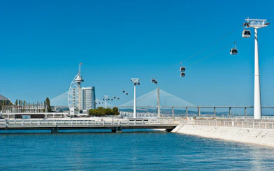 Cable cars over Tagus River with Vasco da Gama Tower and bridge in Lisbon.