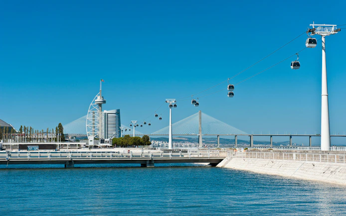 Cable cars over Tagus River with Vasco da Gama Tower and bridge in Lisbon.