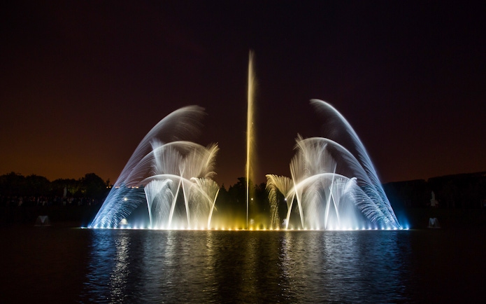 Fountain show at night, Palace of Versailles, with illuminated water jets.