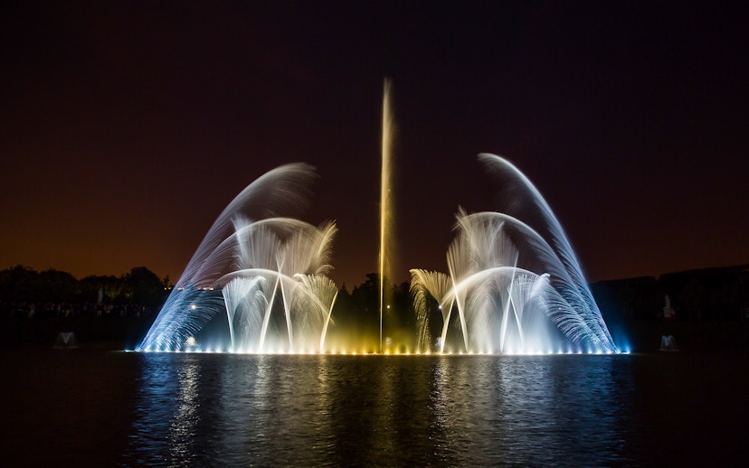 Fountain show at night, Palace of Versailles, with illuminated water jets.