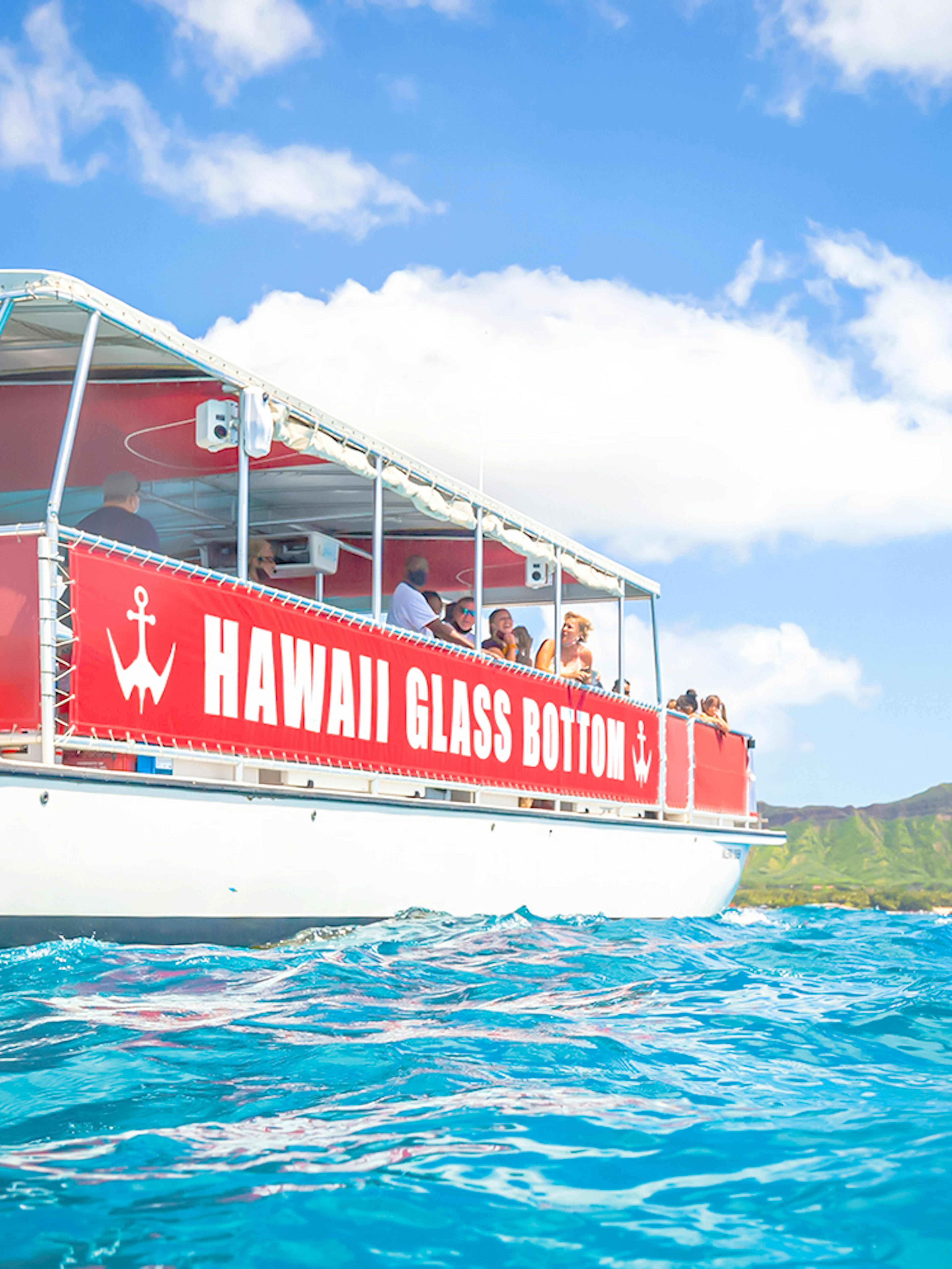 Hawaii glass-bottom boat tour off Waikiki coast with Diamond Head in background.
