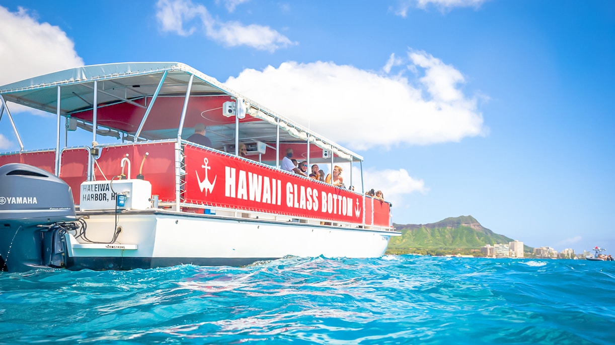 Hawaii glass-bottom boat tour off Waikiki coast with Diamond Head in background.