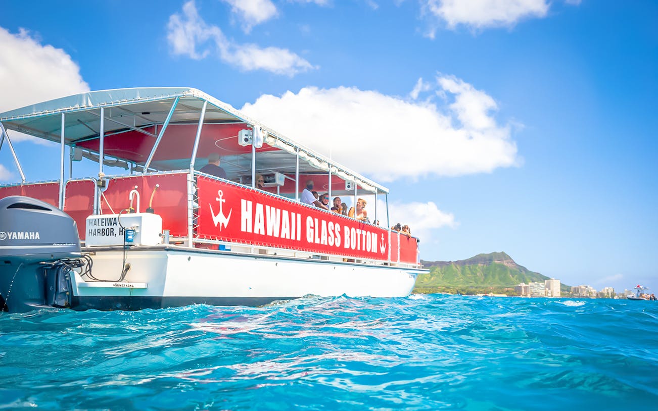 Hawaii glass-bottom boat tour off Waikiki coast with Diamond Head in background.