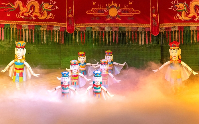 Water puppets performing on stage with colorful backdrop in Vietnam.