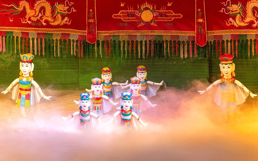 Water puppets performing on stage with colorful backdrop in Vietnam.