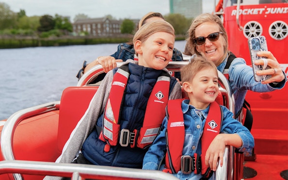 Family enjoying Thames speed boat ride, taking a selfie on the river.