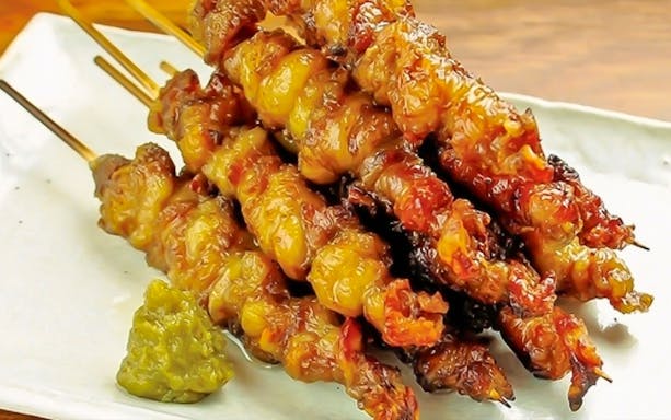 Skewers of grilled meat with a side of green relish, part of a luxury course.