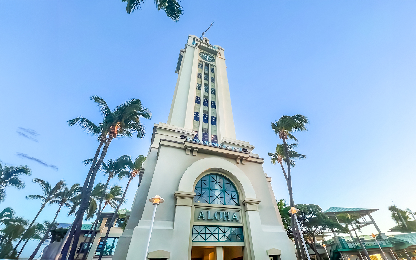 Aloha Tower in Honolulu, Hawaii, surrounded by palm trees under a clear blue sky.