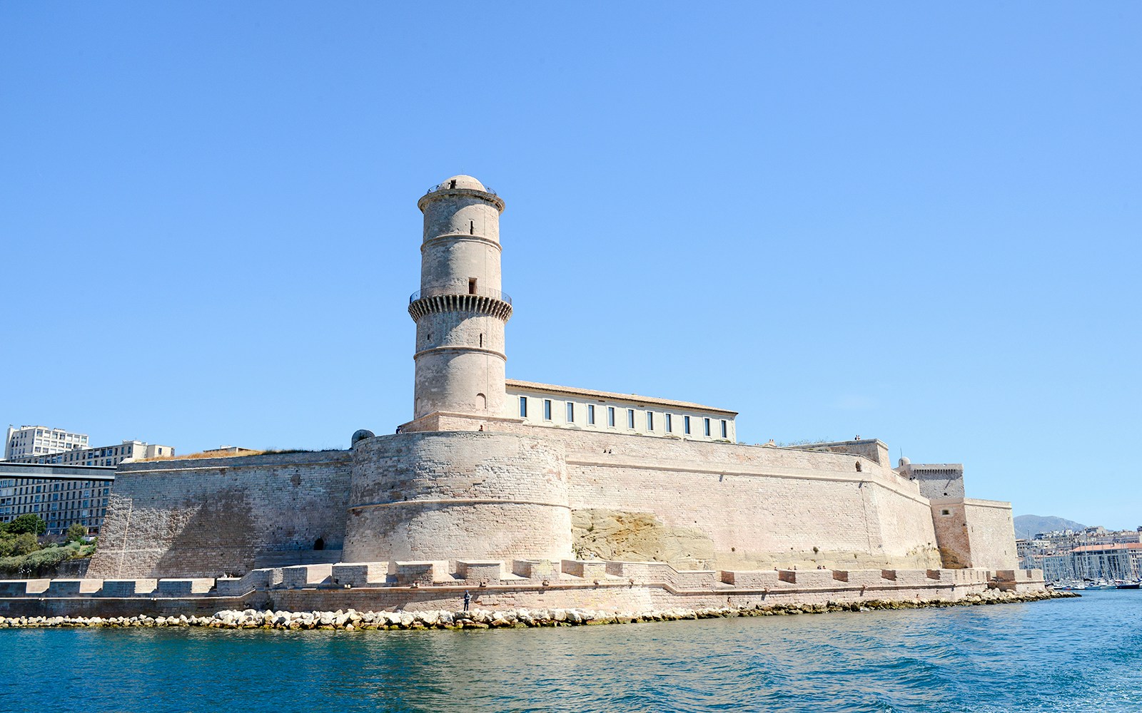 Fort Saint-Jean in Marseille, France, viewed from the water with clear blue sky.