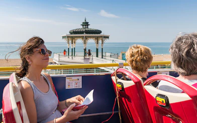 HOHO tour bus passengers at Beach Bandstand, Brighton with sea view.