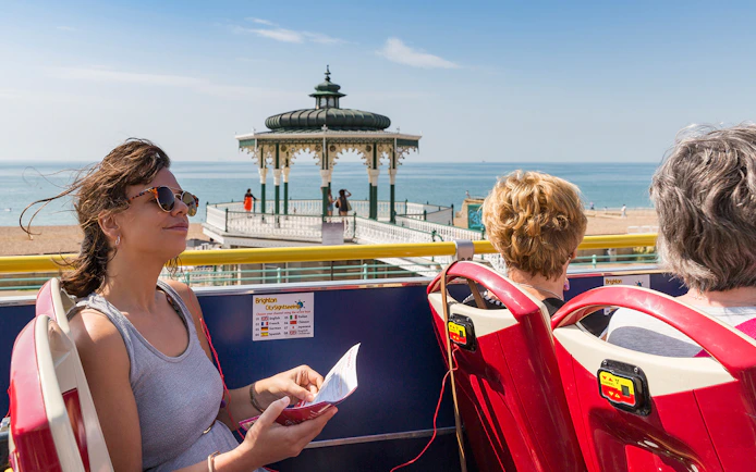 HOHO tour bus passengers at Beach Bandstand, Brighton with sea view.