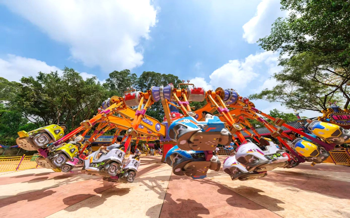 Colorful amusement ride at Chimelong Paradise with spinning cars and trees in the background.