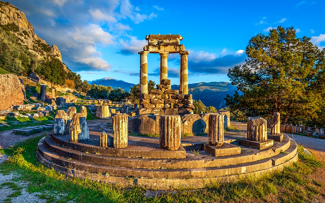 Ruins of the Temple of Athena Pronaia in Delphi, Greece, with surrounding landscape.