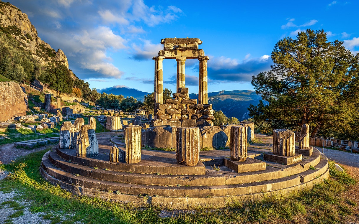 Ruins of the Temple of Athena Pronaia in Delphi, Greece, with surrounding landscape.