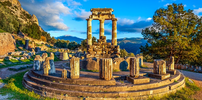 Ruins of the Temple of Athena Pronaia in Delphi, Greece, with surrounding landscape.