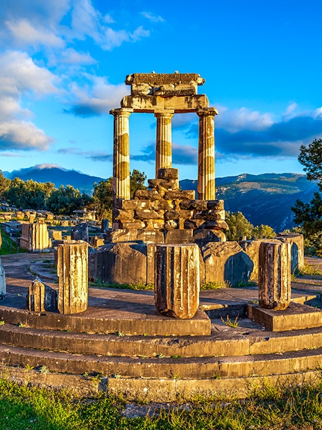 Ruins of the Temple of Athena Pronaia in Delphi, Greece, with surrounding landscape.