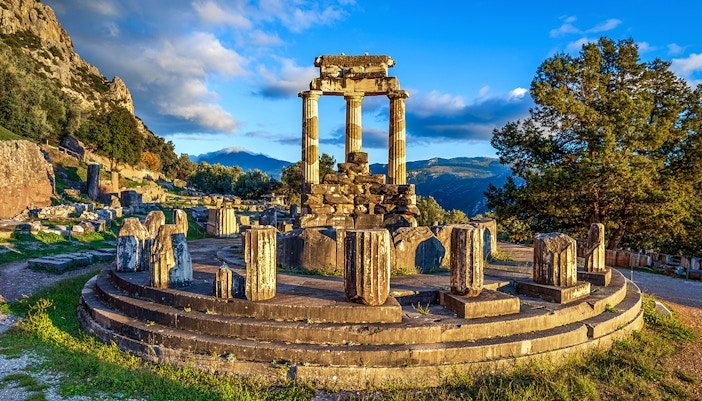 Ruins of the Temple of Athena Pronaia in Delphi, Greece, with surrounding landscape.