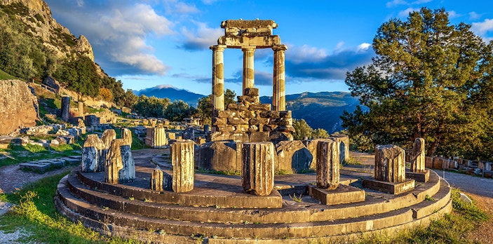 Ruins of the Temple of Athena Pronaia in Delphi, Greece, with surrounding landscape.